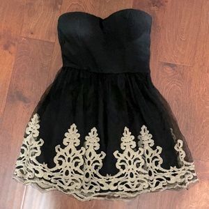 Strapless black dress with gold details around the bottom of the dress.